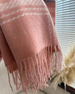 Close-up detail of soft pink cashmere-feel scarf with elegant houndstooth and fringe.