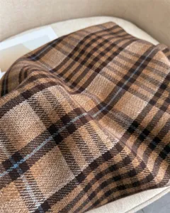 Detailed close-up shot of the soft cashmere-feel plaid scarf texture, premium winter fashion.