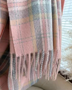 Dettaglio ravvicinato di sciarpa a quadri in ecocashmir morbido con delicate frange.