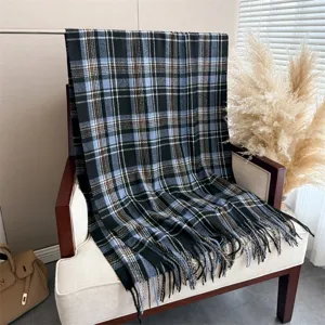 Detailed view of the cozy black and blue plaid cashmere-feel fringed scarf draped on a chair.