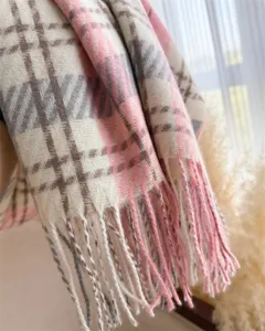 Close-up detail of soft pink beige plaid tassel scarf winter warm cashmere feel fashion accessory.