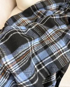 Detailed close-up of the soft blue and black plaid cashmere-like scarf fabric texture.