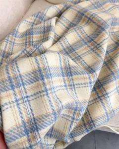 Detailed closeup of a cozy blue and beige plaid cashmere-feel shawl, soft winter scarf fabric.