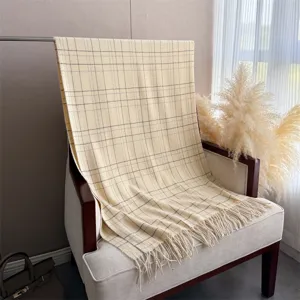 Écharpe à motifs écossais et franges sur fauteuil, vue détaillée de texture douce imitation cachemire.
