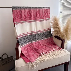 Detail view of winter tassel shawl featuring paisley and geometric patterns on an armchair.