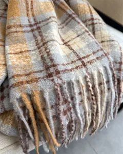 Close-up detail of cozy winter plaid tassel scarf featuring soft boucle yarn texture.