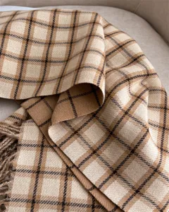 Close-up detail of soft plaid cashmere-feel shawl with tassel edge for winter warmth.