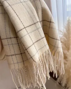 Gros plan détail écharpe hiver cachemire beige à carreaux avec design de franges élégant.