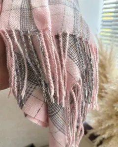 Close-up of pink plaid tassel scarf fabric showing soft texture and delicate fringe details.