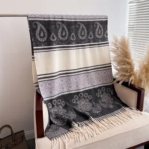 Detailed view of a cozy autumn winter tassel cashmere-feel shawl draped nicely on an armchair.