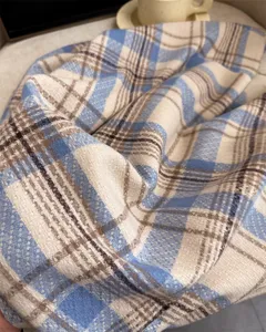 Close up view of soft plaid imitation cashmere scarf fabric texture detail in blue and beige.