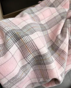 Close-up detail of soft pink plaid cashmere-feel scarf winter warm shawl texture view.