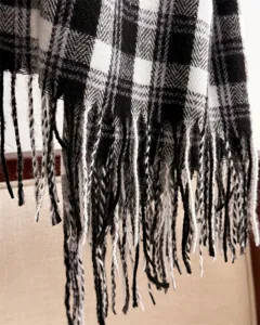 Close-up detail of classic black and white plaid scarf, soft texture and elegant fringe design.