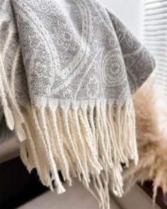 Detailed close-up of grey paisley cashmere-feel winter scarf featuring cream fringe tassels.