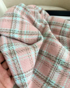 Close-up detail of soft cashmere feel plaid scarf texture in pink blue brown pattern.