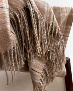 Detailed close-up of a warm autumn winter plaid fringed scarf, soft cozy cashmere-like texture.