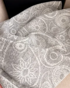 Close-up of grey cashmere-feel winter scarf with detailed paisley pattern texture.