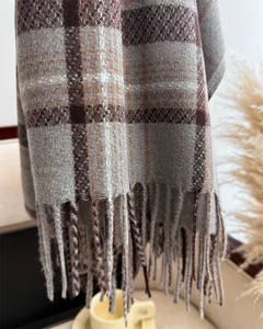 Detailed view of winter plaid scarf texture, soft cashmere-feel fabric with neat fringe ends.