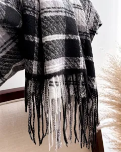 Close-up detail of soft monochrome plaid tassel scarf texture and fringe design for winter style.