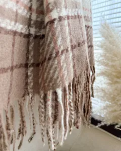 Brown plaid blanket scarf detail shot, soft boucle fabric, fringe hem texture close up.