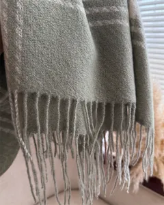 Sage green winter scarf close up, soft loop yarn fabric detail with classic fringe trim.