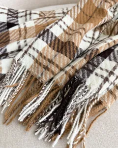 Close-up of cozy faux cashmere plaid scarf with stylish fringe trim, soft autumn winter accessory.