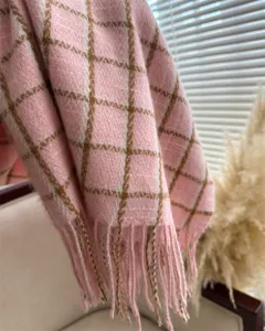Nahaufnahme eines kuscheligen rosa karierten Schals mit Fransen, weiches Winterhalstuch.