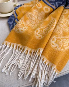 Close-up detail of soft autumn winter tassel scarf with warm yellow floral pattern.