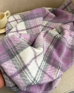 Detail shot of a cozy purple plaid cashmere-feel winter scarf, soft texture and warm winter style.