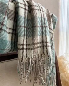 Detailed shot of classic plaid cashmere-feel tassel scarf showing soft warm winter texture.