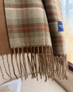 Close-up detail of autumn winter plaid tassel scarf showing soft cashmere-feel fabric texture.