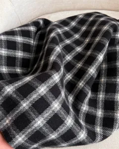 Detailed close-up of classic black and white plaid cashmere-feel winter scarf fabric texture.