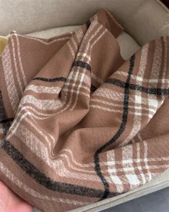 Detailed view of the soft brown plaid cashmere-like winter scarf, showing cozy warmth and texture.