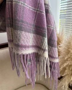 Close-up detail of the cozy winter plaid cashmere-feel scarf showing soft texture and tassels.