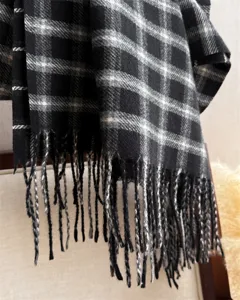 Close-up detail of a classic black and white plaid fringe scarf, soft texture and warm winter.