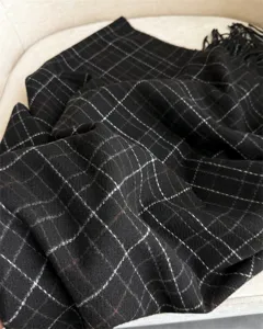 Gros plan détaillé d'une écharpe douce à carreaux noirs avec de jolies franges.