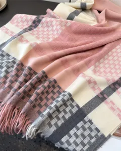Close-up of soft plaid tassel scarf detail, showing cozy cashmere texture and elegant pink tone.