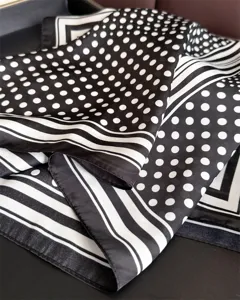Gros plan d'un carré de soie à pois noirs et blancs, accessoire de foulard élégant.