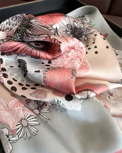 Detailed close-up of a floral print silk square scarf, showcasing the smooth fabric and elegant design.