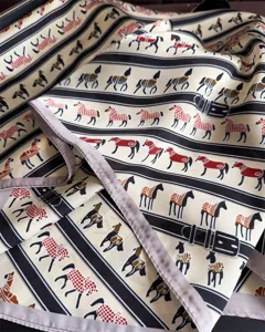 Vue rapprochée d'un foulard en soie de luxe avec des motifs élégants de chevaux et de ceintures.