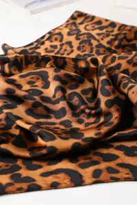 Leopard print silk feel scarf close up, luxurious satin texture fashion shawl detail view.