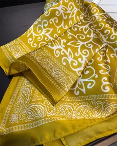 Close-up detail of a yellow satin square scarf featuring elegant white paisley scroll prints.
