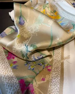 Detailed close-up shot of golden silk square scarf featuring delicate floral and dragonfly print.