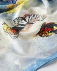 Elegant silk scarf detail view featuring vibrant butterfly print and delicate jacquard fabric.
