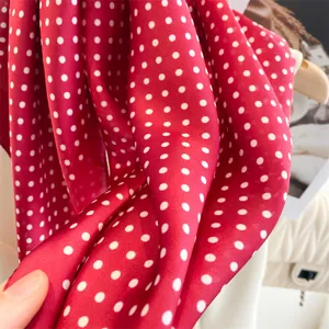 Dettaglio foulard di seta a pois rossi, tessitura liscia, design elegante e classico.