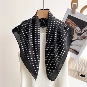 Dettaglio della sciarpa quadrata in seta a pois neri e bianchi, elegante texture per il collo.