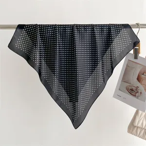 Primo piano dettagliato di un classico foulard quadrato in seta con pois bianchi.
