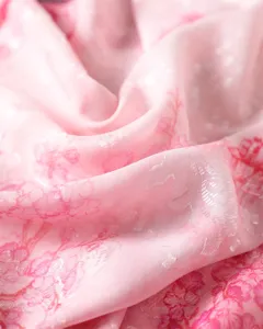 Pink floral jacquard silk scarf fabric detail showing delicate cut-work and smooth texture.