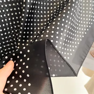 Primo piano dettagliato della texture del tessuto di un foulard di seta a pois bianchi.