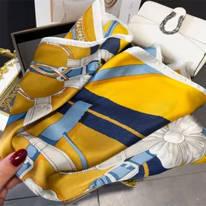 Close-up detail of luxury horse bit print silk square scarf, elegant yellow and blue styling.